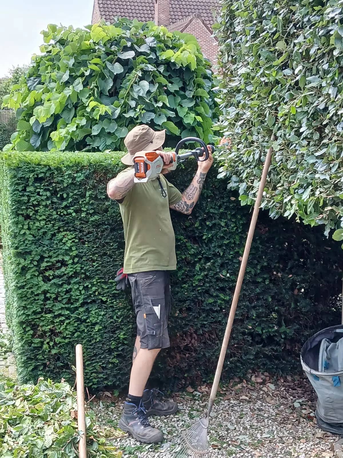 Kristof snoeit een hoge haag in een particuliere tuin